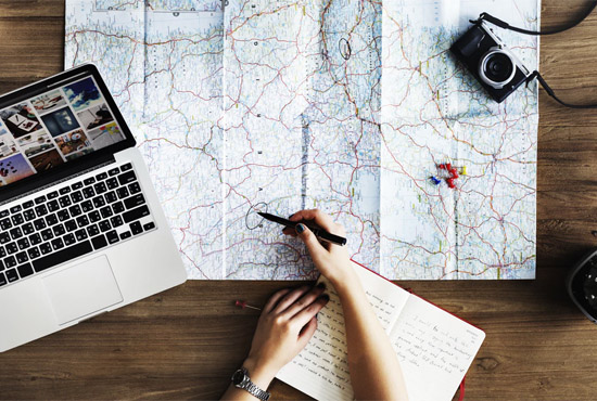 Overhead view of table with map spread out and laptop to the side